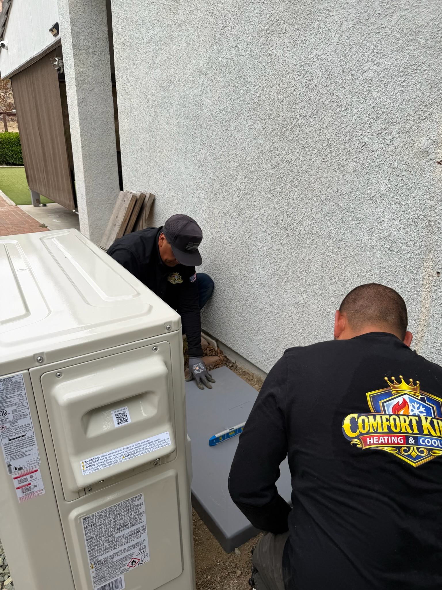 Comfort Kings technician setting a new pad for an outdoor unit