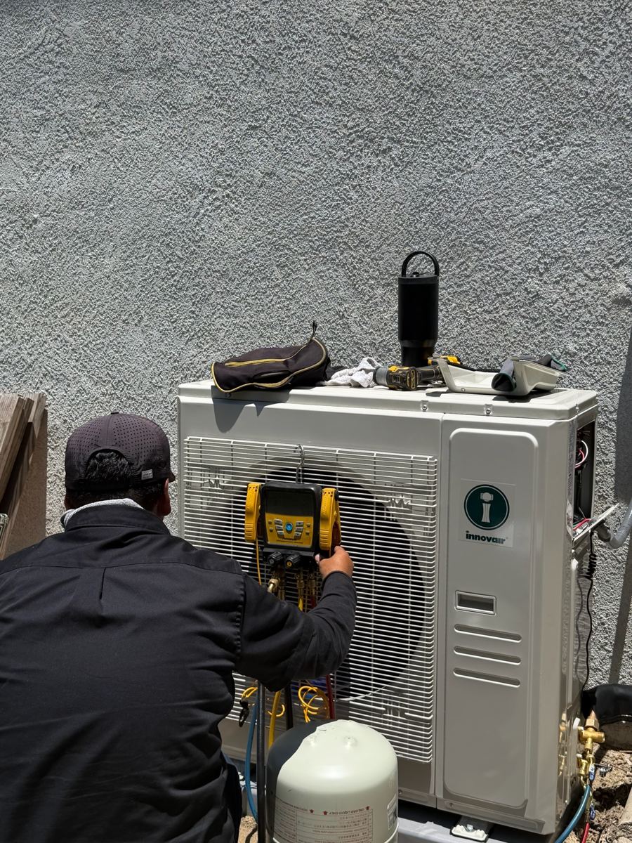 Técnico cargando refrigerante en la unidad exterior de una bomba de calor nueva